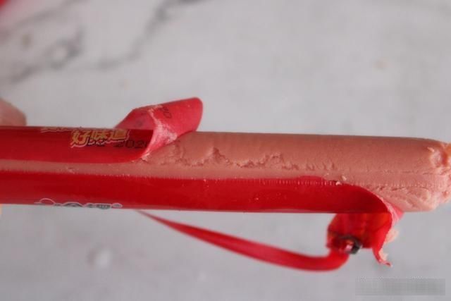 接下来我们|吃了这么久火腿肠,才知道按一下这地方,外皮一碰就开了,真简单